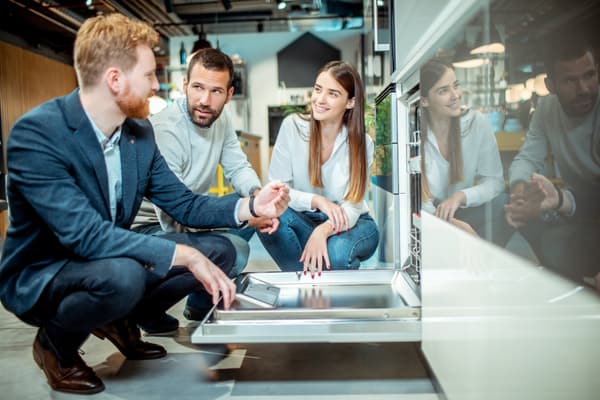 An appliance salesman showcasing a dishwasher to a couple